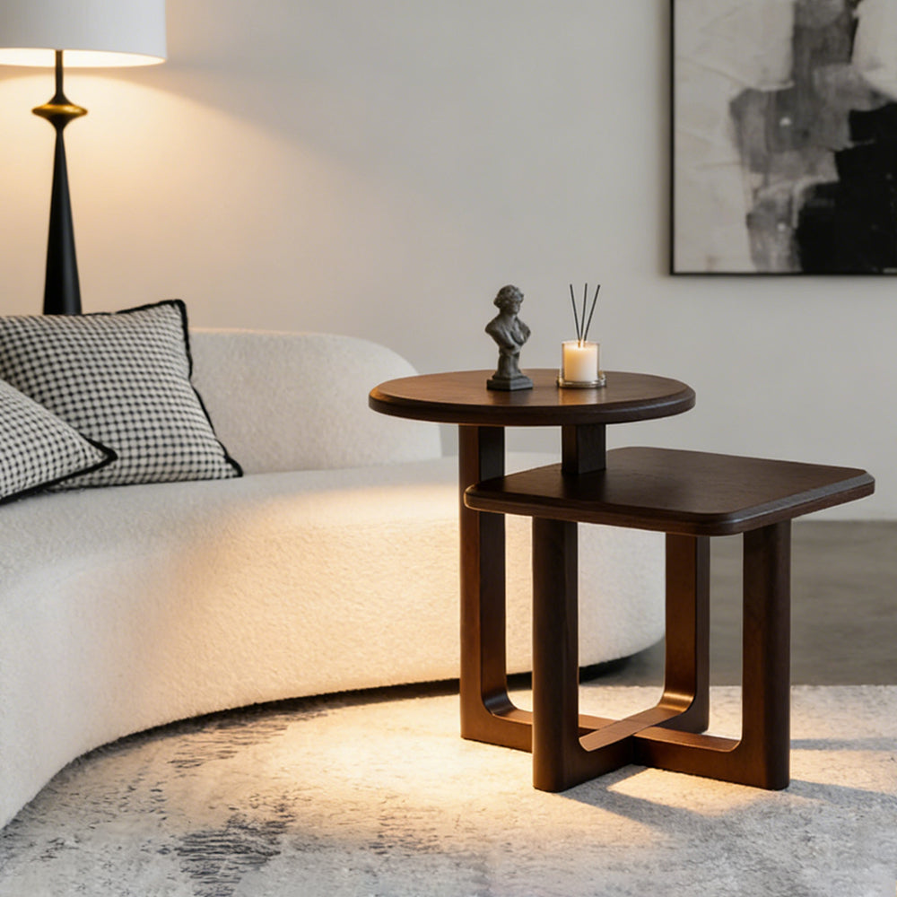 Modern living room with curved cream sofa and nested wooden side tables, styled with candle, diffuser, and minimalist decor.