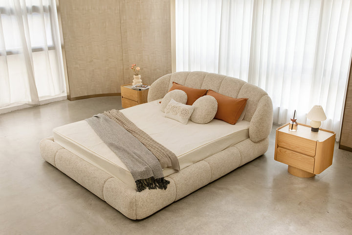 Rangka ranjang platform mewah dengan upholstery bouclé warna netral, proporsi seimbang, headboard bersayap membulat, dan sisi empuk halus untuk kesan nyaman dan homey.