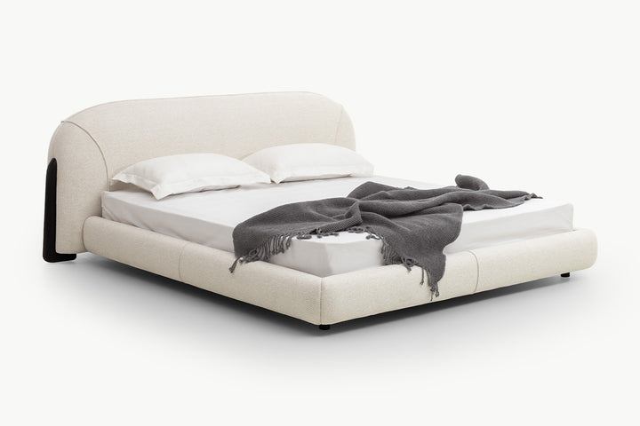 Low-profile platform bed frame in neutral beige upholstery with black legs and seamless padded sides, emphasizing clean lines and comfortable support