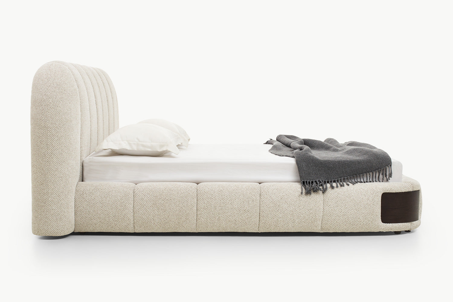 Modern platform bed with generously padded frame in neutral textured fabric, rounded edges, and integrated wood accents for a cohesive luxurious look