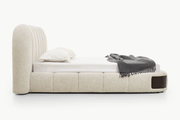 Modern platform bed with generously padded frame in neutral textured fabric, rounded edges, and integrated wood accents for a cohesive luxurious look