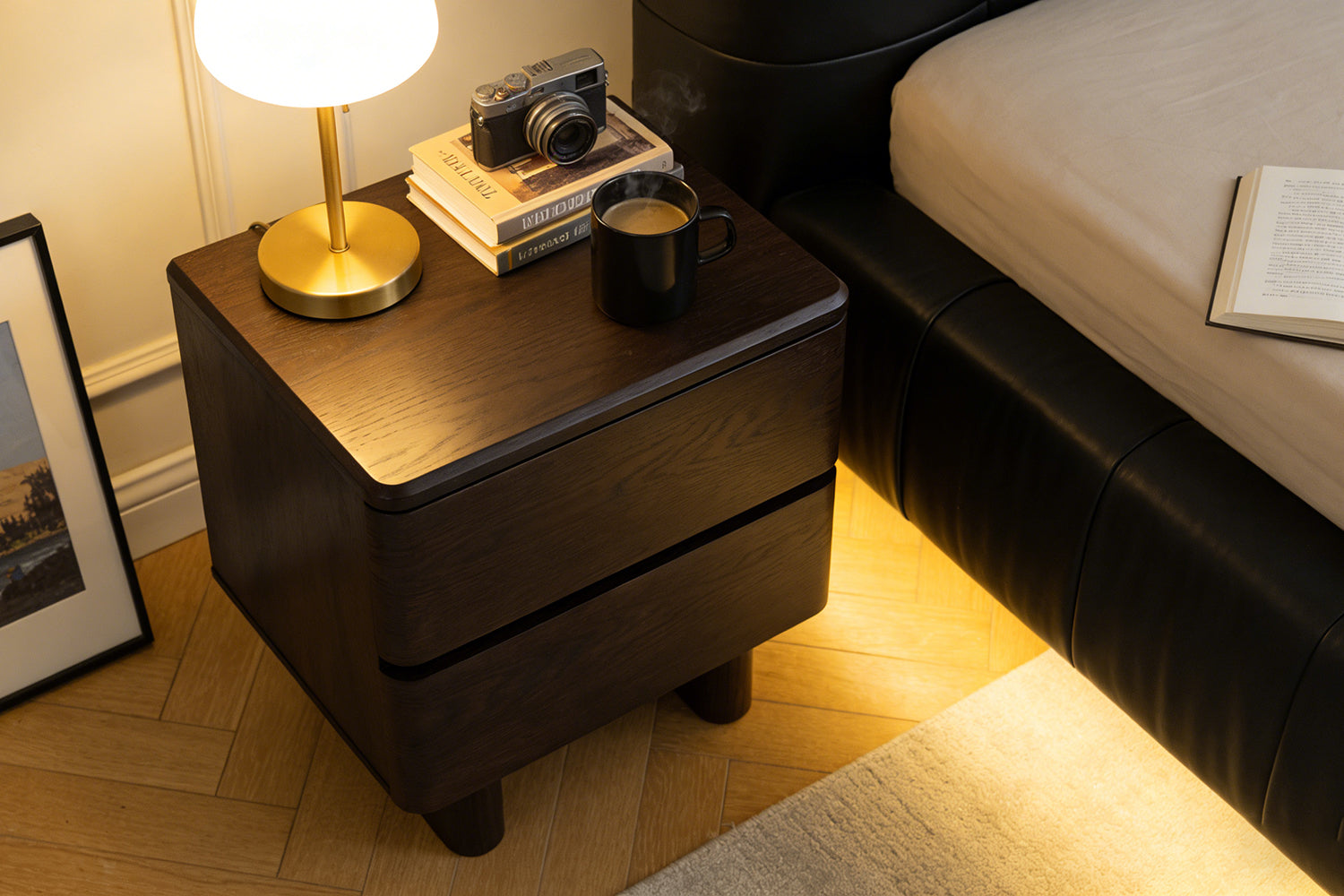 Nakas Chris kayu oak gelap dalam setting kamar tidur, dengan lampu meja kuningan emas, kamera vintage, tumpukan buku, dan cangkir kopi hitam—gaya modern yang cozy