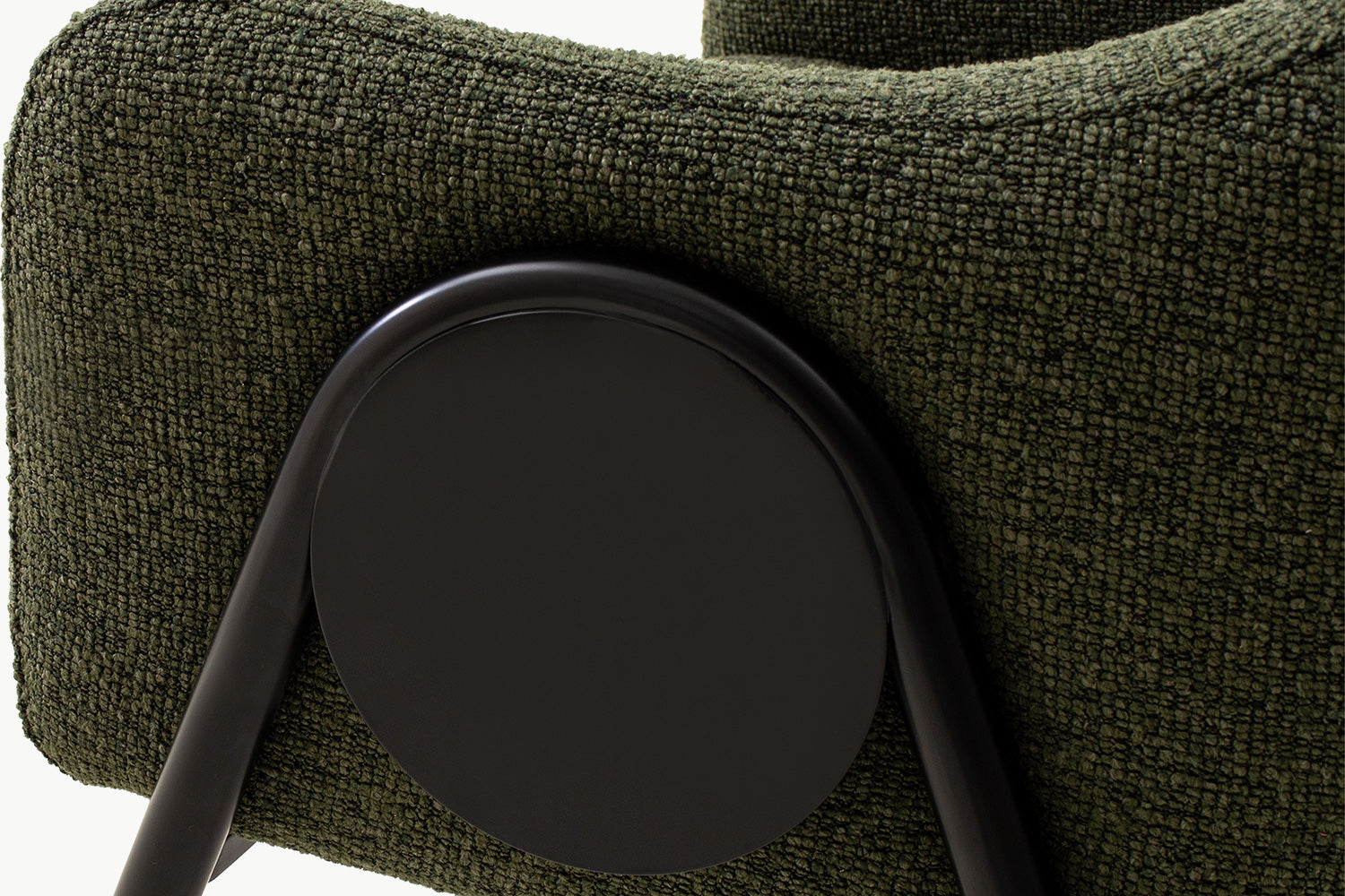 Close-up detail of the high-quality dining chair's signature black circular accent connecting the boucle-upholstered arm to the sleek black metal legs, showcasing premium craftsmanship and thoughtful design.