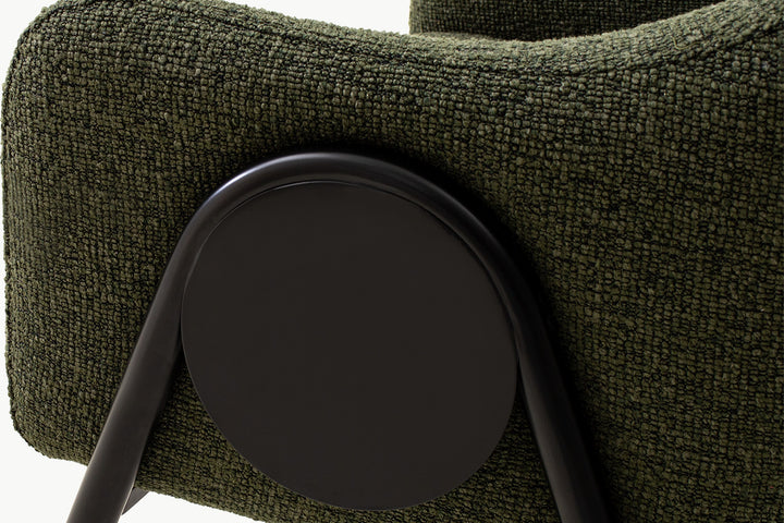 Close-up detail of the high-quality dining chair's signature black circular accent connecting the boucle-upholstered arm to the sleek black metal legs, showcasing premium craftsmanship and thoughtful design.