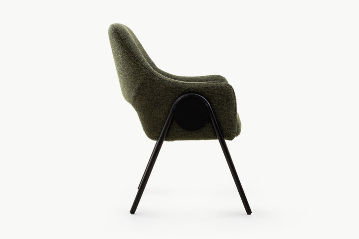 Side view of the olive dining chair highlighting its sculptural curved form, plush textured fabric, black metal splayed legs, and unique circular black accent for added contemporary flair.